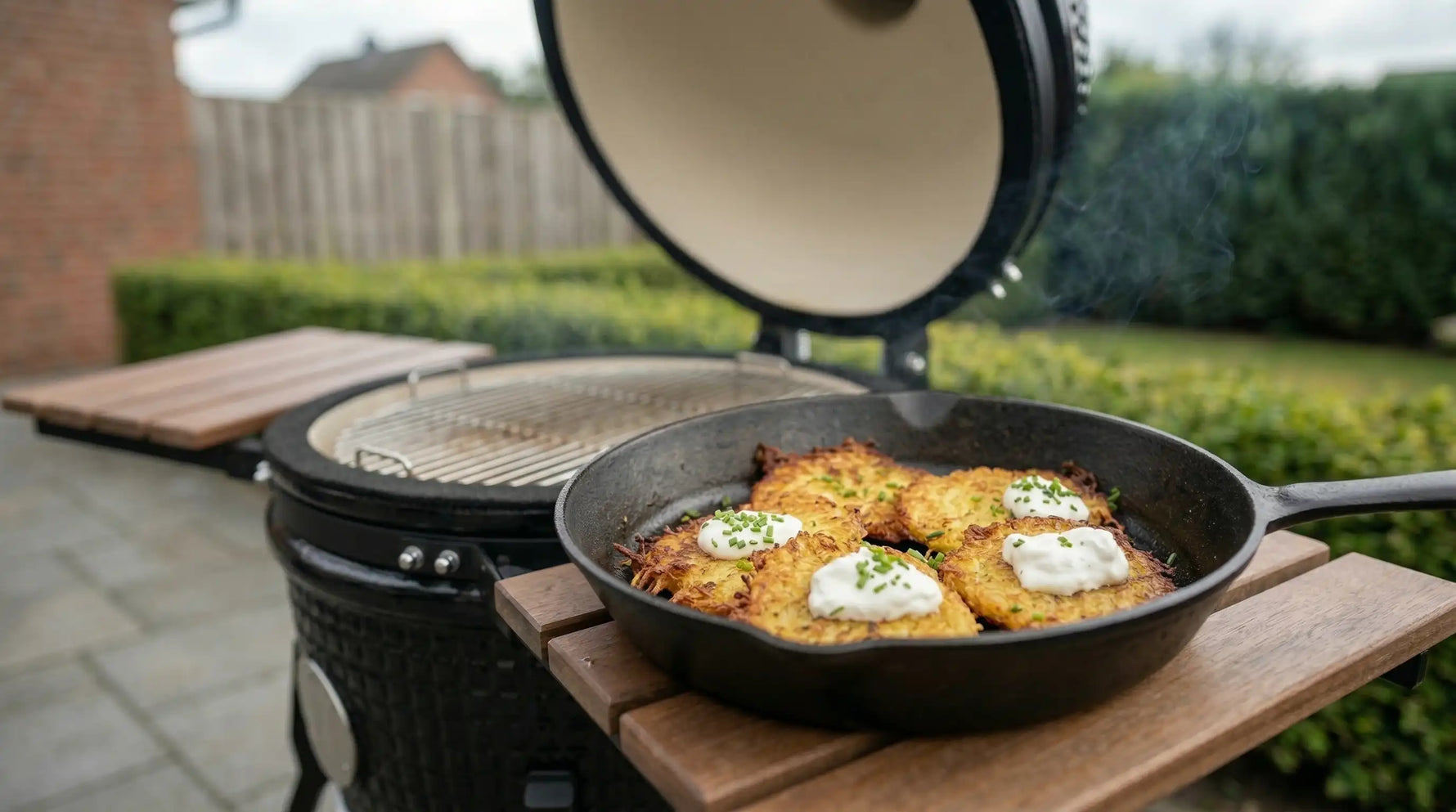 Galettes de pommes de terre croustillantes en poêle en fonte sur Kamado Forest Grill ouvert en extérieur, avec crème et ciboulette