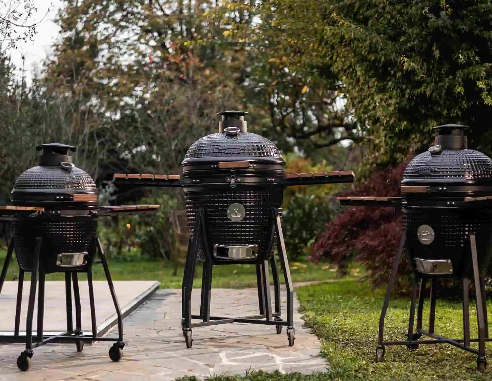 kamado en céramique sur terrasse, braises incandescentes et fumée au crépuscule