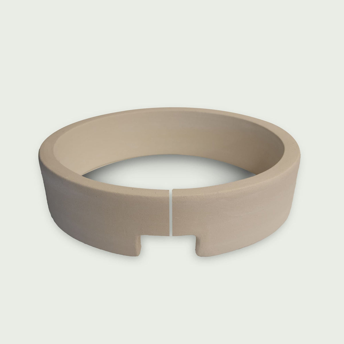 Anneau en céramique pour kamado, de couleur beige, avec encoche frontale et séparation visible pour faciliter l’installation et le maintien des éléments de cuisson.