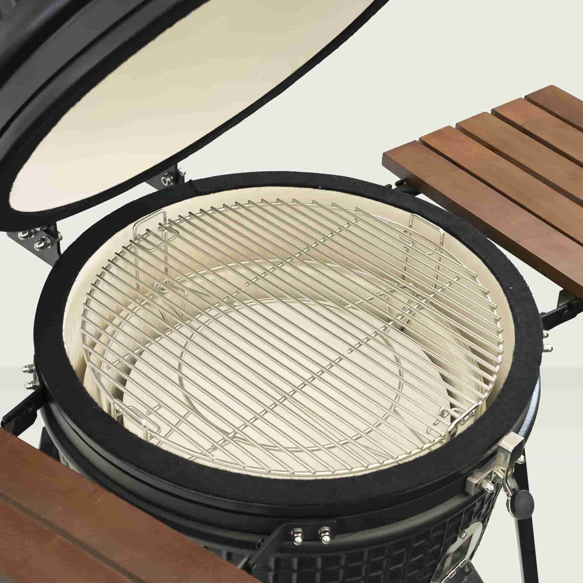 Intérieur d’un barbecue Kamado 22" ouvert, avec grille de cuisson en acier inoxydable et déflecteur en céramique pour une cuisson indirecte uniforme.