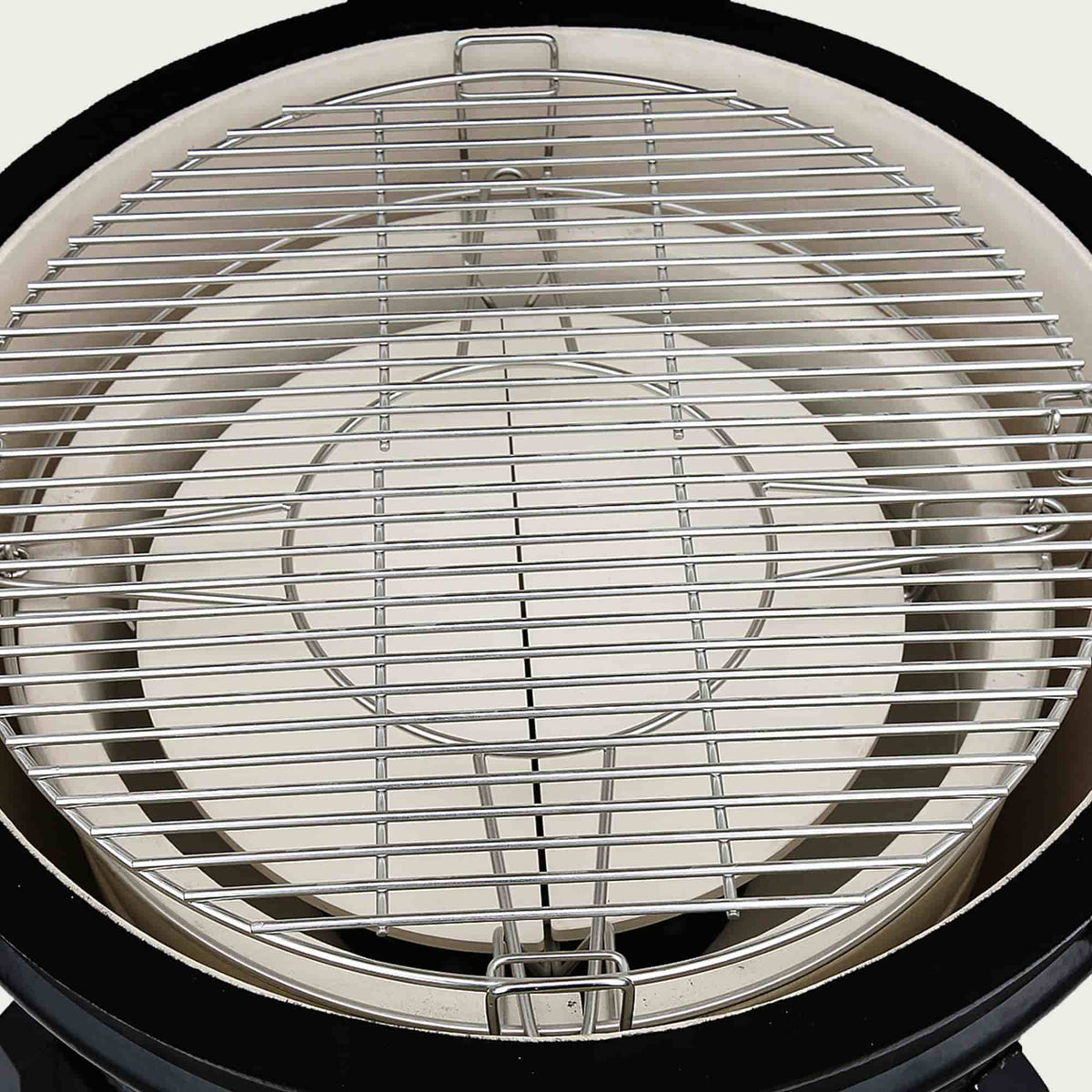 Vue intérieure du Kamado Forest Grill équipée d’une grille de cuisson en inox massif et d’une pierre déflectrice en céramique épaisse, idéale pour la cuisson indirecte.