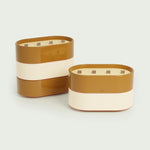 Bougies Totem L Forest en Brun terre de sienne et Beige ivoire, parfums Citronnelle & Fleur d’oranger et Citronnelle & Citron, au design raffiné et aux finitions brillantes, avec trois mèches en bois.