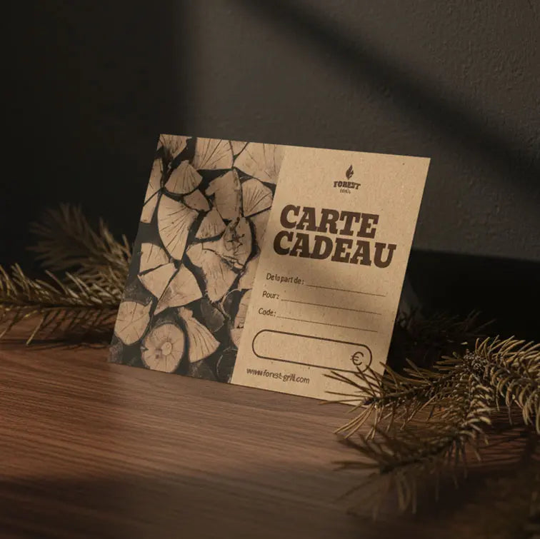 Carte cadeau Forest Grill en papier recyclé, posée sur une table en bois avec décor naturel, idéale pour offrir un barbecue ou un kamado