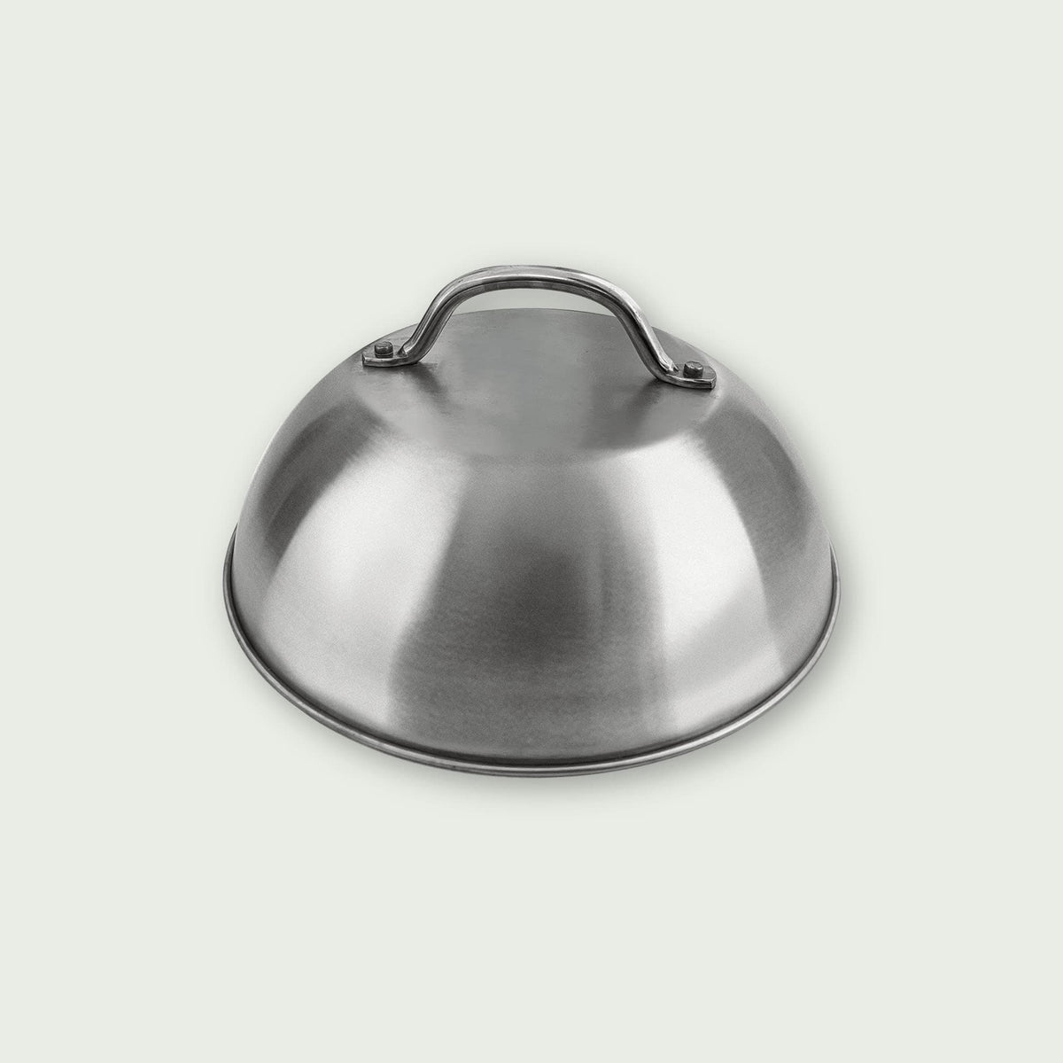 Cloche de cuisson en acier inoxydable avec poignée sur le dessus, présentée sur fond clair, idéale pour maintenir les aliments au chaud sur la plancha ou le barbecue.