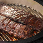 Cuisson de côtes levées caramélisées sur la grille en inox du Kamado Forest Grill, révélant une texture juteuse et un fumage parfaitement maîtrisé.