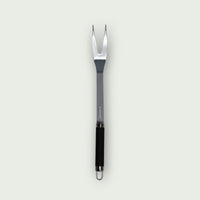 Stainless steel meat fork with ergonomic black handle and perforated tip for hanging.