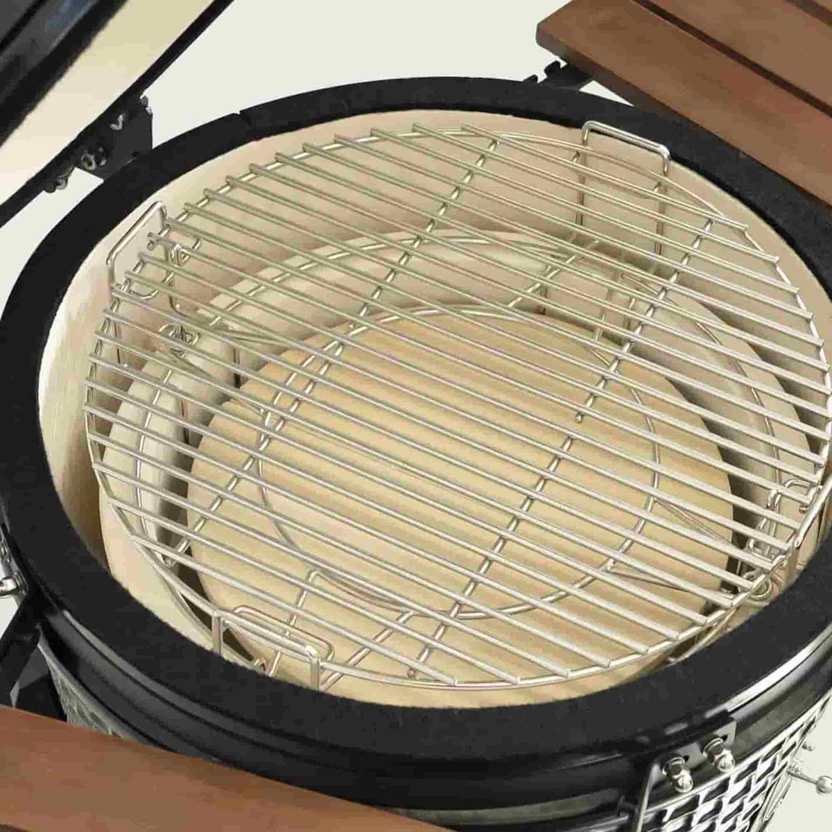 Vue de dessus de l’intérieur d’un barbecue Kamado avec une grille de cuisson en acier inoxydable et des éléments en céramique épaisse pour une cuisson homogène et durable.