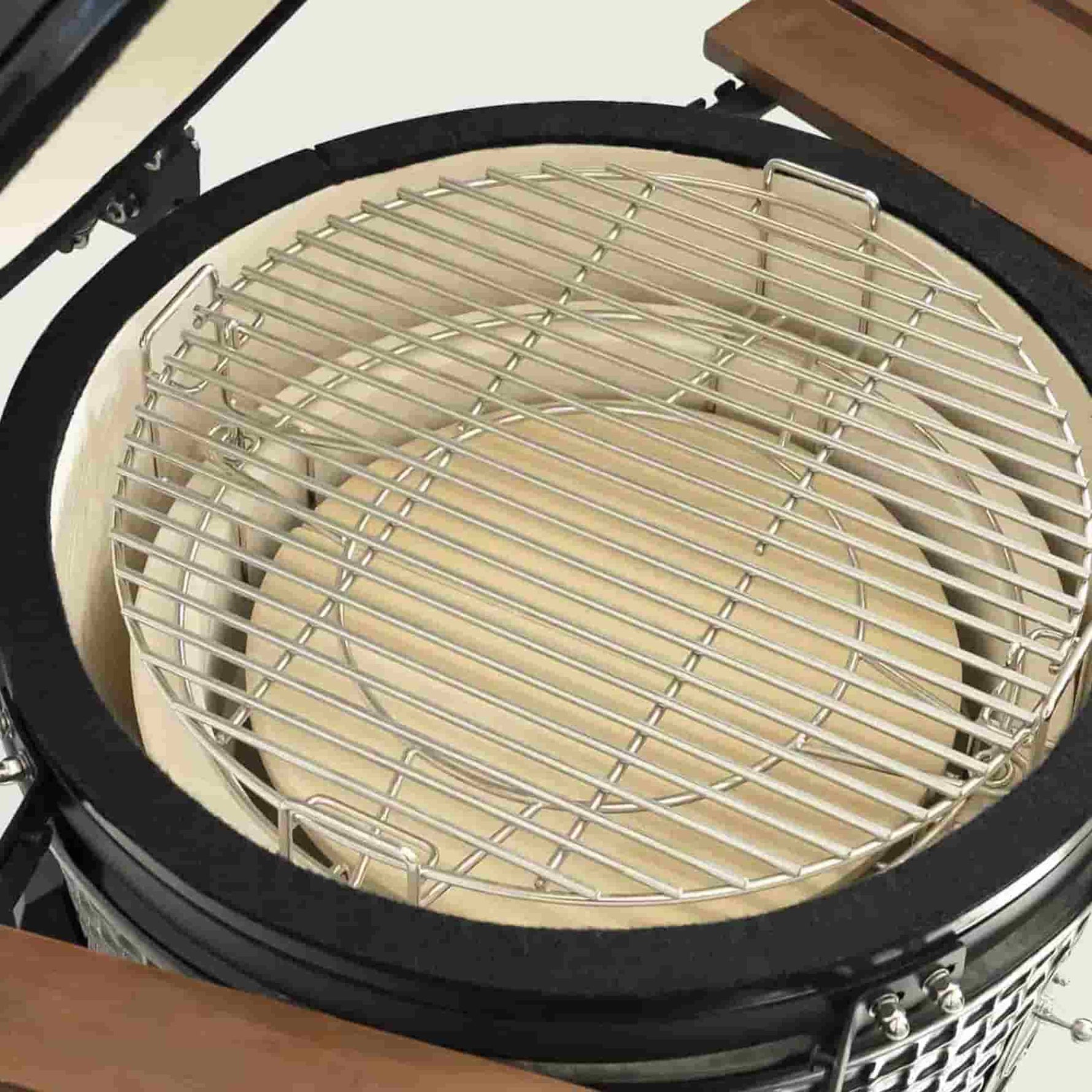 Vue de dessus de l’intérieur d’un barbecue Kamado avec une grille de cuisson en acier inoxydable et des éléments en céramique épaisse pour une cuisson homogène et durable.