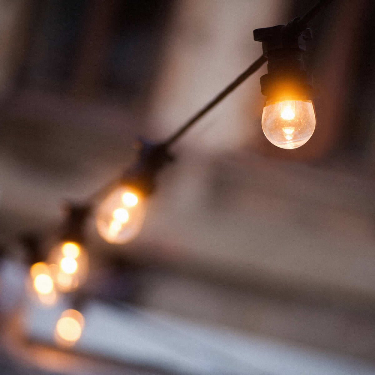 Guirlande lumineuse extérieure avec ampoules rondes à filament, suspendue en ligne et diffusant une lumière chaude et tamisée, parfaite pour créer une ambiance douce et conviviale en soirée.