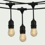 Gros plan sur une guirlande lumineuse extérieure Forest Grill avec ampoules LED en forme de goutte, suspendues à un câble noir robuste, diffusant une lumière chaude et douce pour une ambiance conviviale.