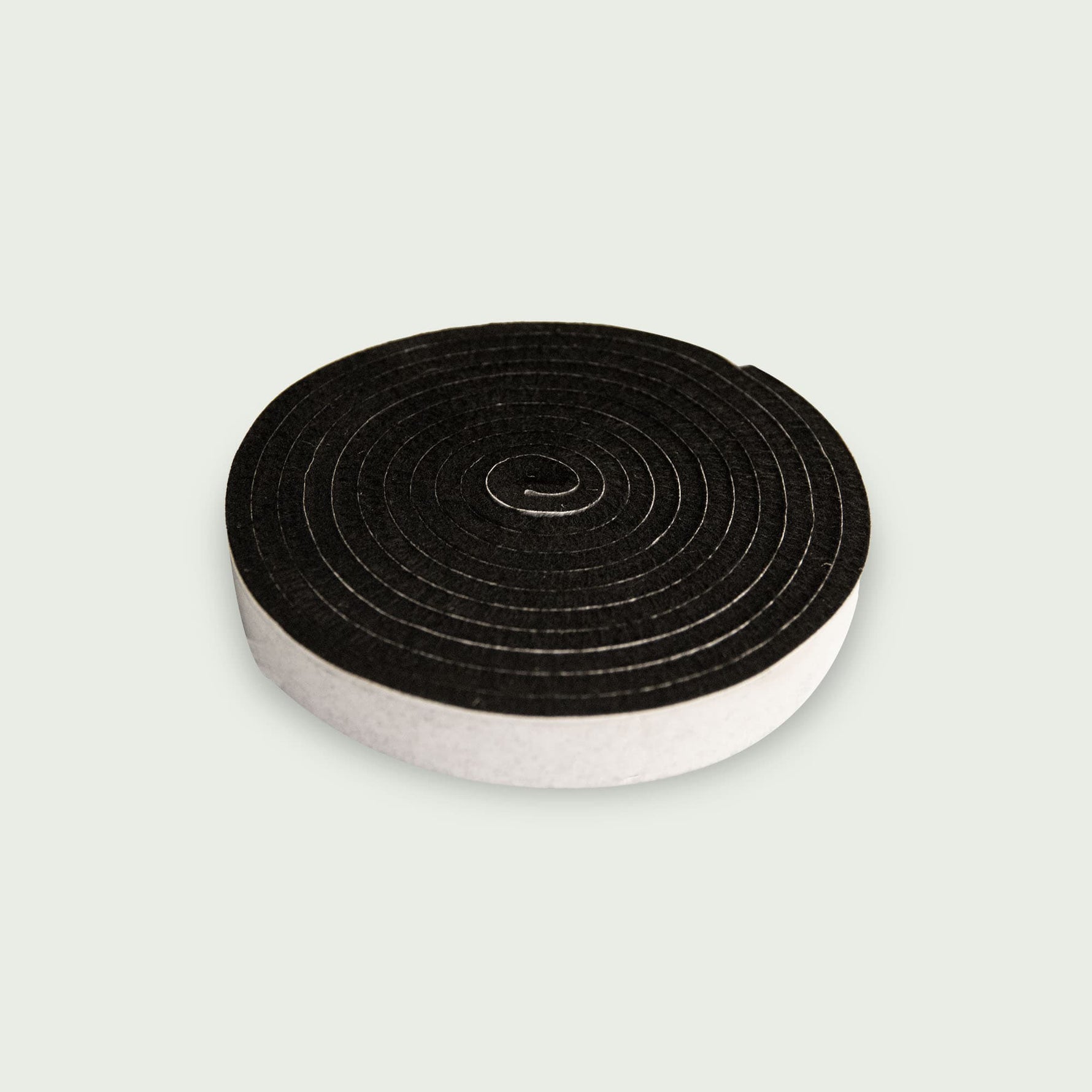 Rouleau de joint en feutre noir pour kamado, présenté en spirale sur fond clair.