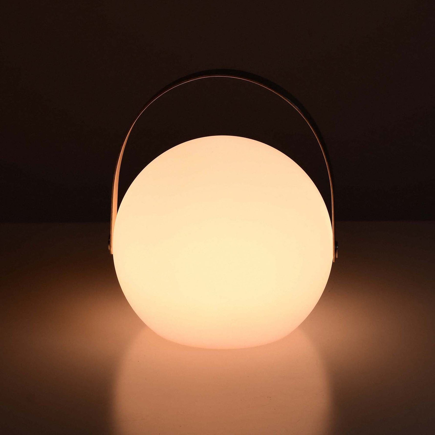 Lampe d’extérieur ronde Forest Grill allumée, diffusant une lumière chaude et apaisante à travers son globe blanc mat.