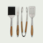Ensemble de quatre ustensiles de barbecue en acier inoxydable avec manche en bois : brosse de nettoyage, fourchette, pince et spatule.