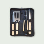 Coffret de 4 ustensiles de barbecue avec manches en bois clair, comprenant pince, spatule, couteau et fourchette, rangés dans une housse de transport pratique.