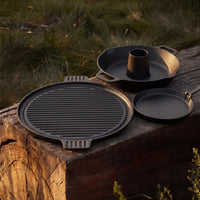 Forest Grill cast-iron cooking set with reversible plancha, cast-iron skillet and chicken stand on an outdoor wooden table