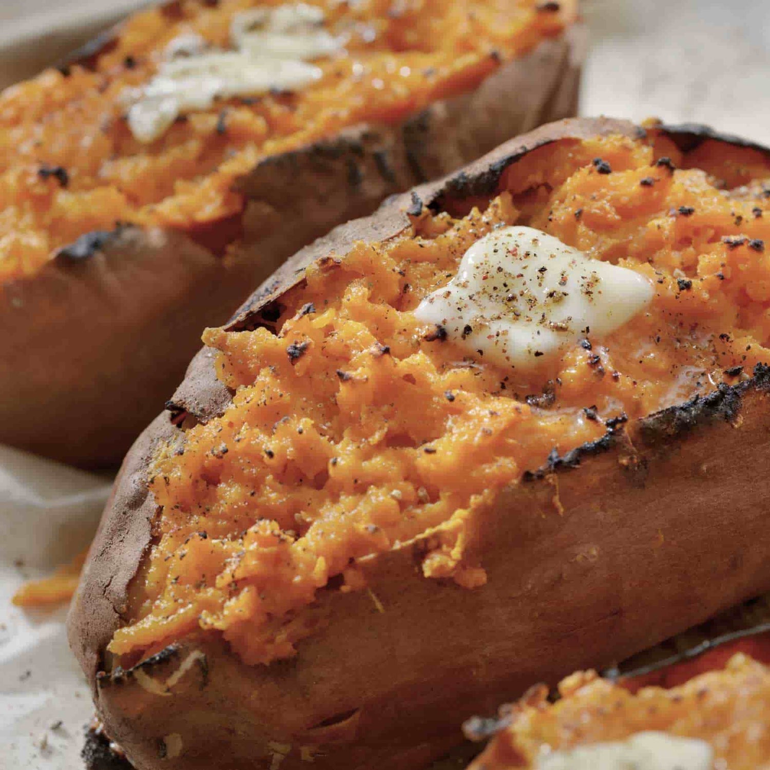 Patates douces grillées au barbecue Kamado Forest Grill, garnies de beurre fondant et relevées d’une touche de poivre.