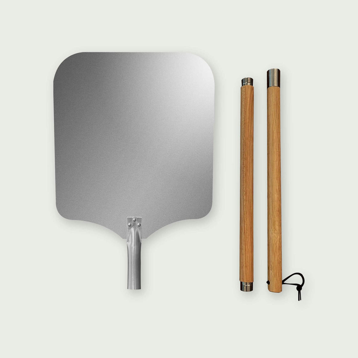 Pelle à pizza en aluminium avec grand plateau rectangulaire arrondi et manche en bois démontable posé à côté, idéale pour enfourner et sortir facilement les pizzas du four ou du Kamado.