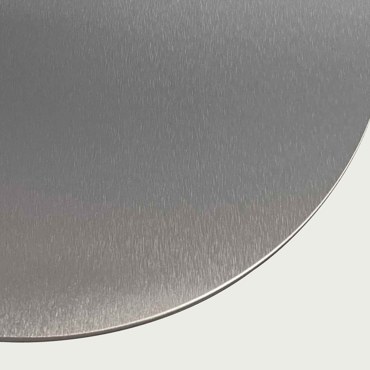 Gros plan sur la surface en inox brossé de la pelle à pizza, soulignant la finition lisse et résistante du métal.