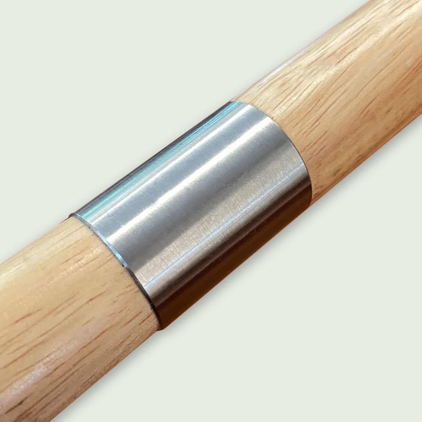 Détail du manche en bois avec bague de renfort en inox d’une pelle à pizza, combinant solidité, élégance et confort de prise en main.