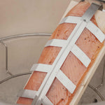 Planche de fumage en bois avec un filet de saumon maintenu par un support inox, prête pour une cuisson lente et aromatique à l’intérieur du barbecue kamado.