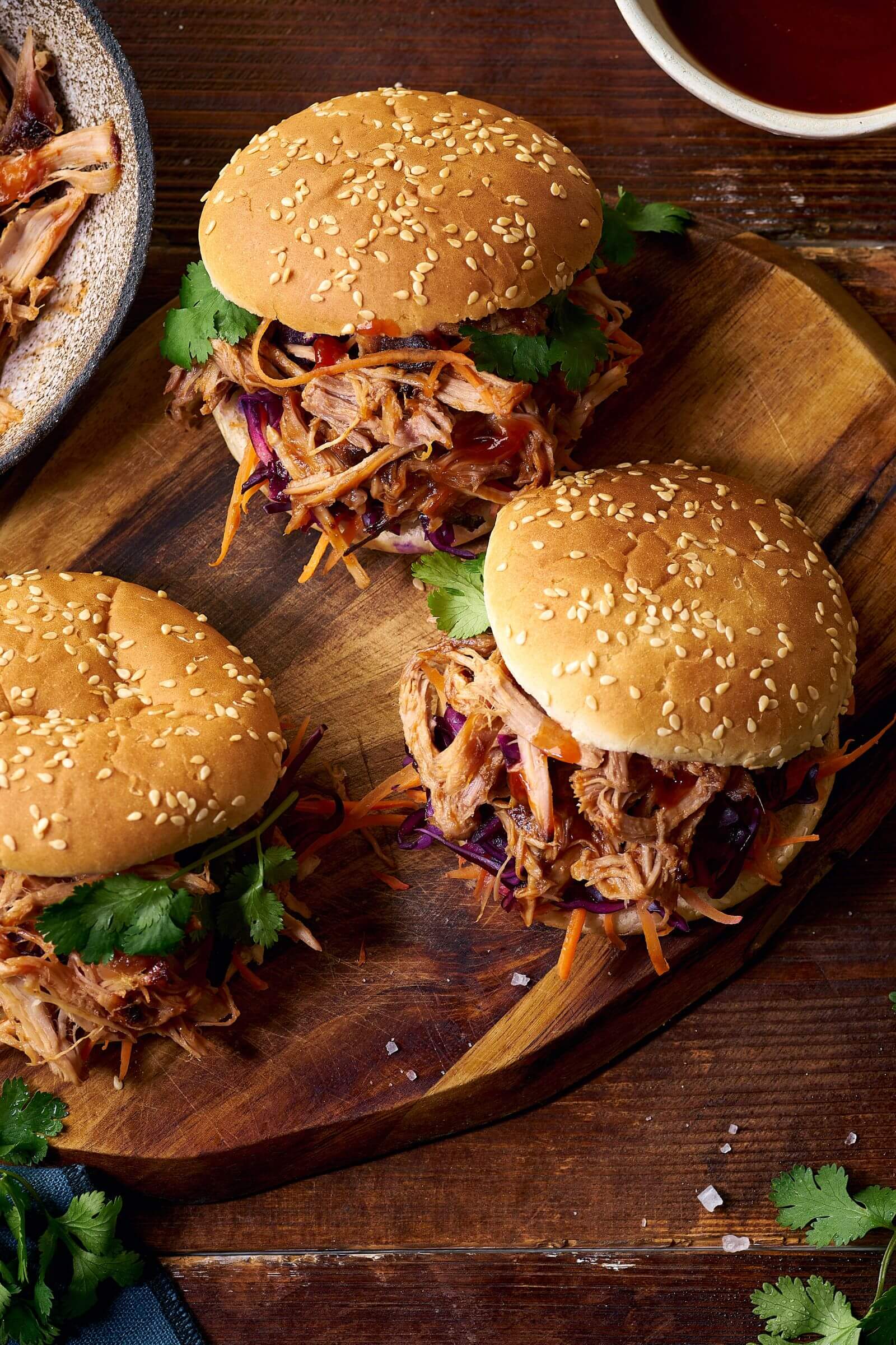 Burgers au pulled pork effiloché avec sauce barbecue, coriandre fraîche et crudités colorées.