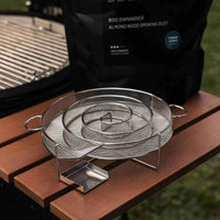 Stainless steel smoking coil placed on a wooden shelf, used for cold smoking with almond wood sawdust.